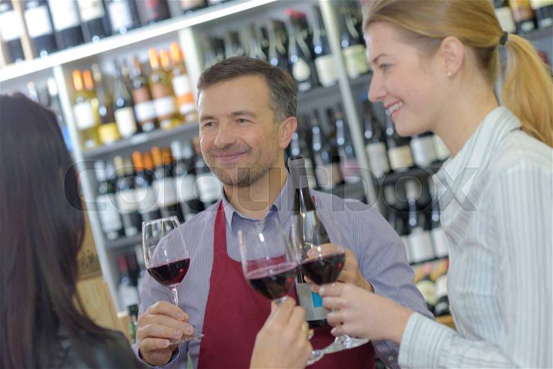 Young people toasting red wine with merchant in cellar, stock photo
