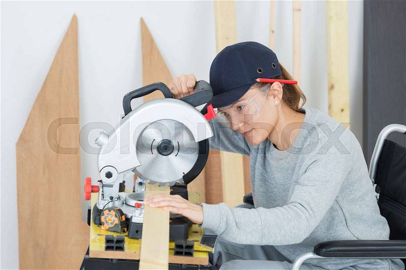 Woman carpenter using circular saw, stock photo
