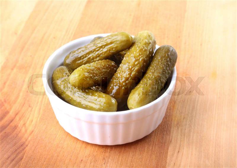 Bowl with pickled gherkins, cucumbers on wooden background close up. Pickles, stock photo