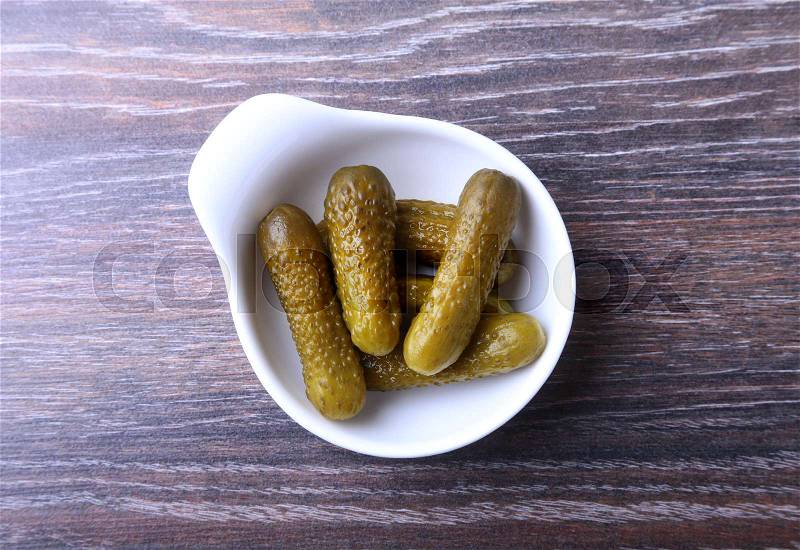 Bowl with pickled gherkins, cucumbers on wooden background close up. Pickles, stock photo