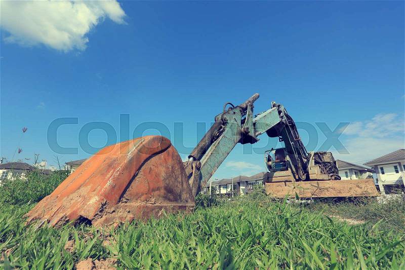 Old excavator construction machinery of industry parked on grass field, stock photo