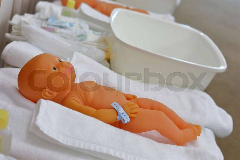 Baby doll in nursery class room with parents training child care infant, stock photo