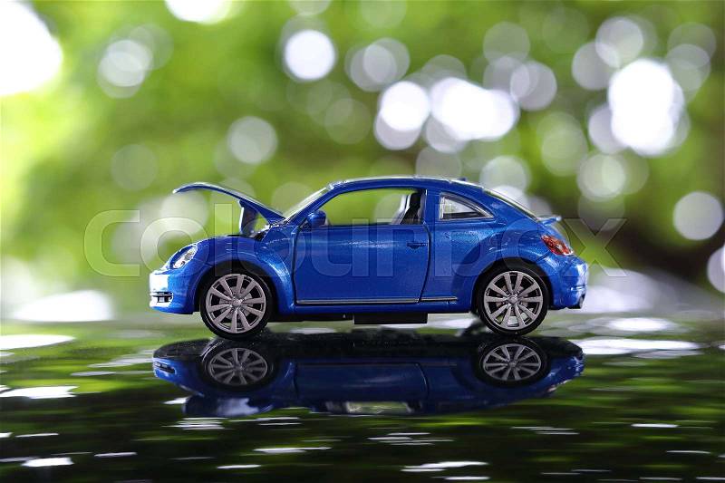 Miniature car toy problem broken down parked with open hood of vehicle waiting for repair service in green nature blur bokeh background, stock photo