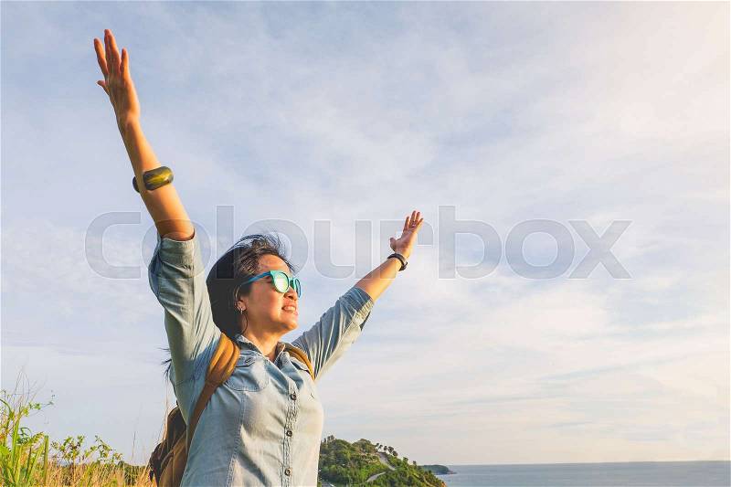 Happy young traveler woman raised arm up to sky enjoying a beautiful of nature at top of mountain and sea view,Freedom wanderlust backpacker concept,vintage filter, stock photo
