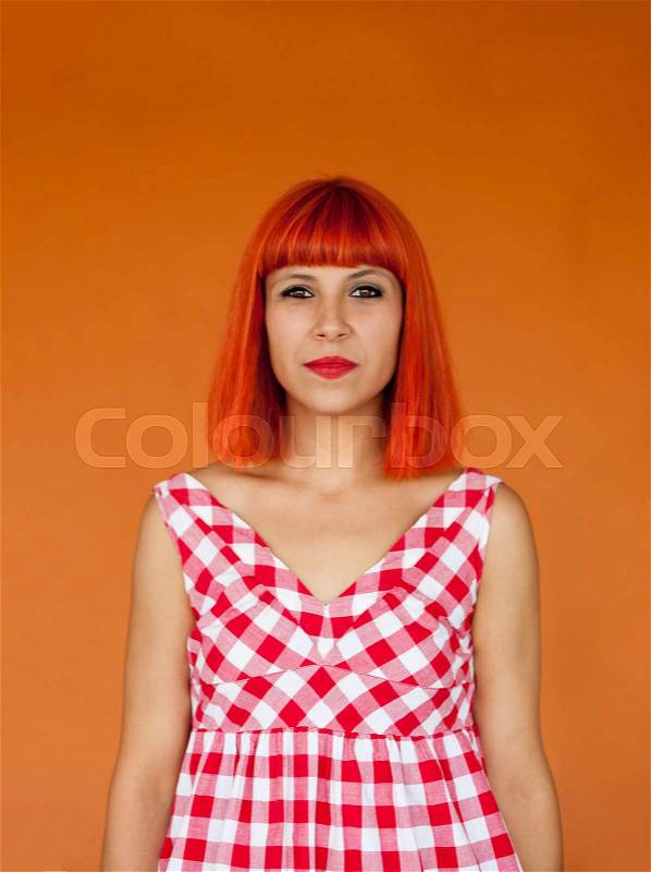 Red haired woman with red checkered dress on a orange background, stock photo