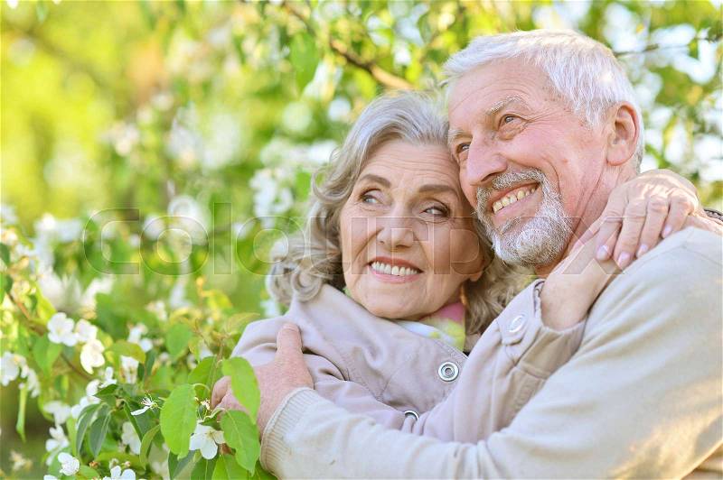 Portrait of happy senior couple standing under blooming tree, stock photo
