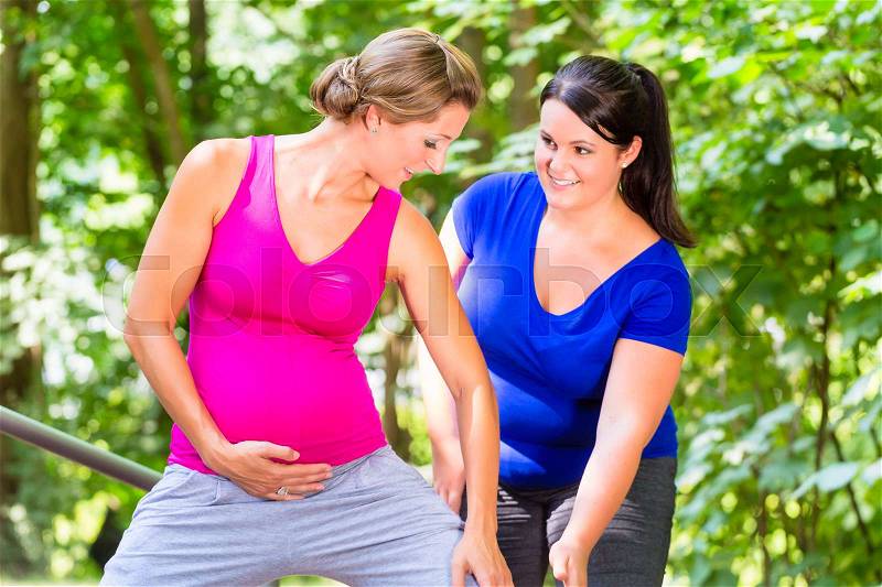 Women doing pregnancy fitness exercises together in park, stock photo