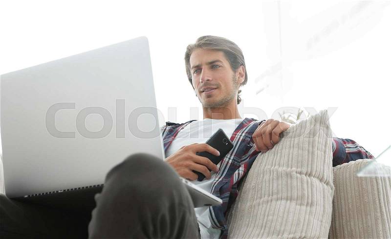 Successful guy sitting on sofa in living room. Photo has a blank space for text, stock photo