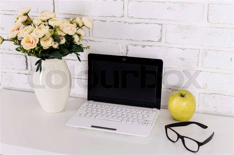 Workplace with modern laptop over white brick wall, stock photo