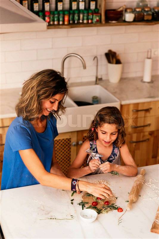 Little girl cooking with her mother in the kitchen. Infant Chef Concept, stock photo