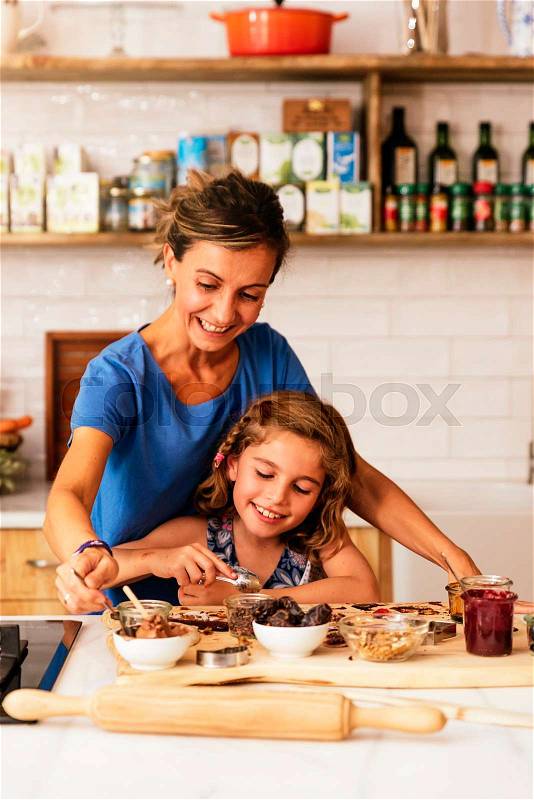 Little girl cooking with her mother in the kitchen. Infant Chef Concept, stock photo