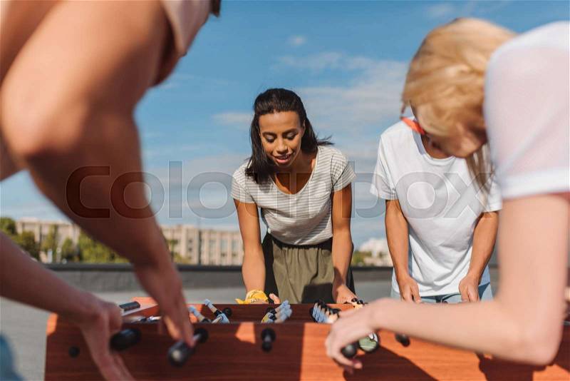 Happy young friends playing table football on roof, stock photo