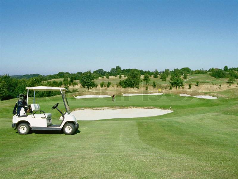 Electric golf buggy parked on the fairway of a golf course, stock photo