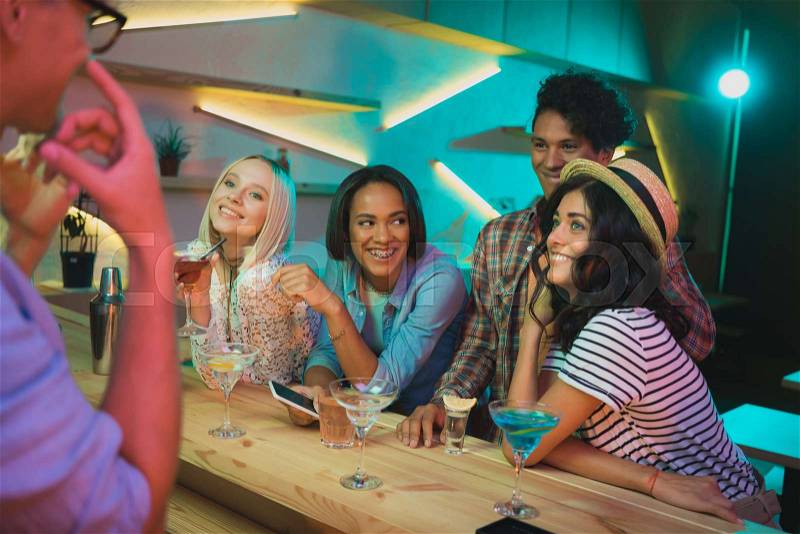Smiling multicultural friends with drinks spending time together in bar, stock photo
