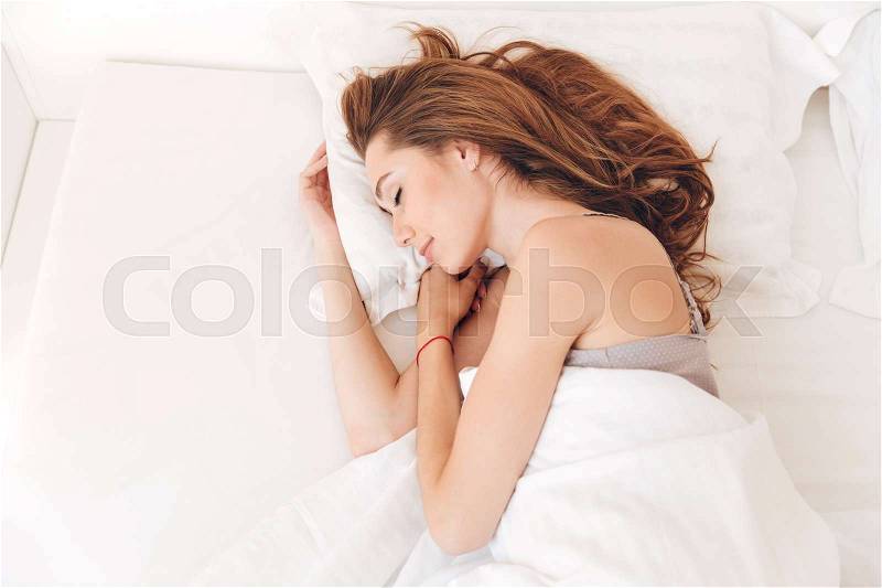 Picture of young smiling pretty lady sleep in bed indoors. Eyes closed, stock photo