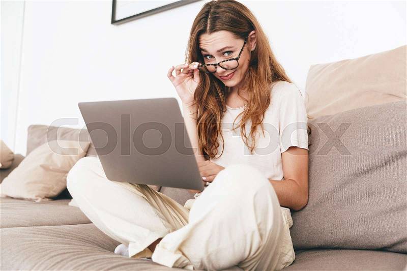 Young beautiful casual businesswoman in eyeglasses work with laptop at home, stock photo