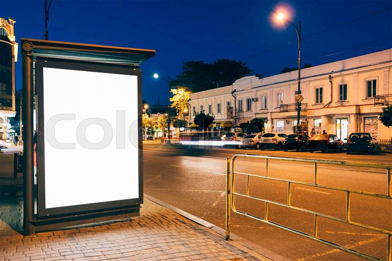 Blank advertising display at a bus stop in the city at night, stock photo