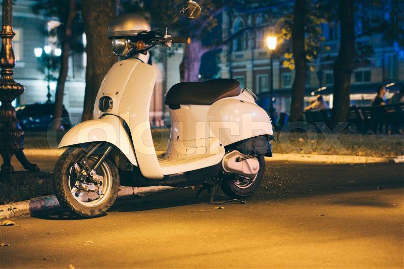 White motor scooter in a night city in summer, stock photo