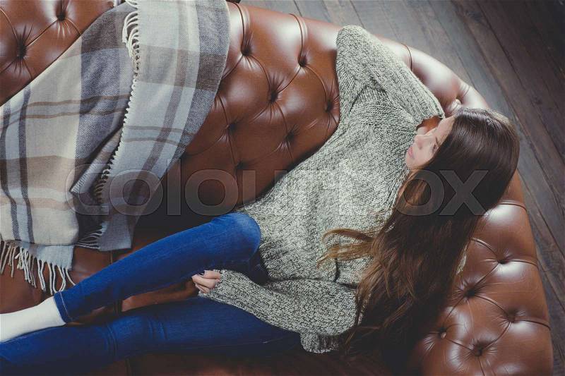 Beautiful woman lying at sofa wearing warm clothing. Relax time during cold weather, stock photo