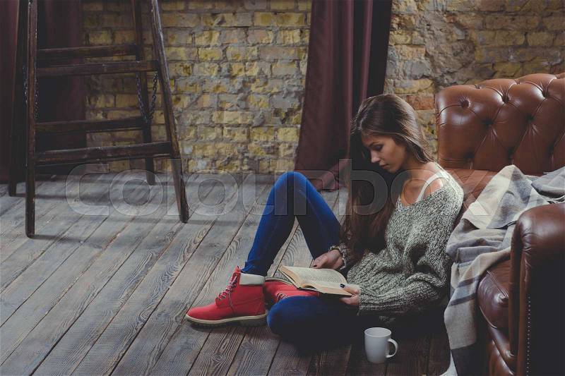 Beautiful woman reading a book wearing warm clothing. Relax time during cold weather, stock photo