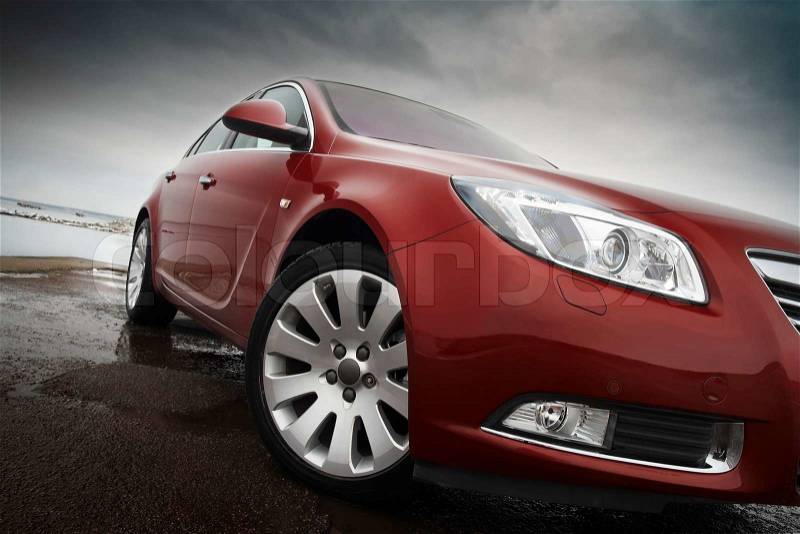 Cherry red car front detail with big light alloy wheel, stock photo