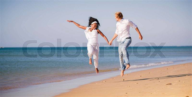 Couple in vacation on beach, black woman and white man running, stock photo