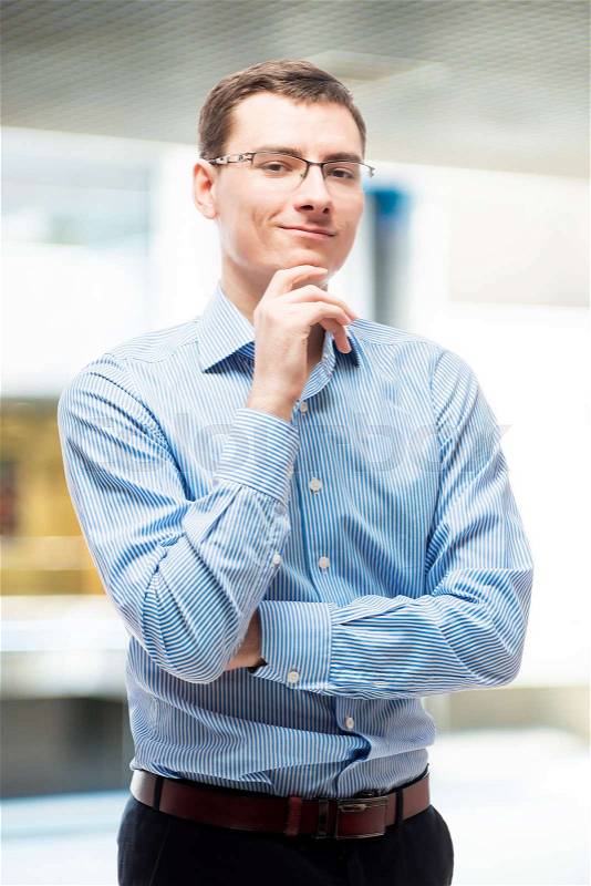 Portrait of smiling businessman in blue striped shirt in office, stock photo