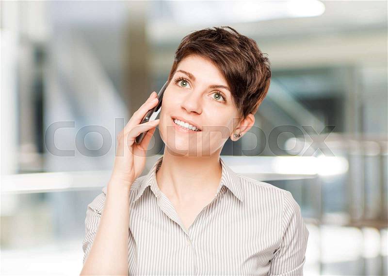 Happy woman with mobile phone and space left in the office, stock photo
