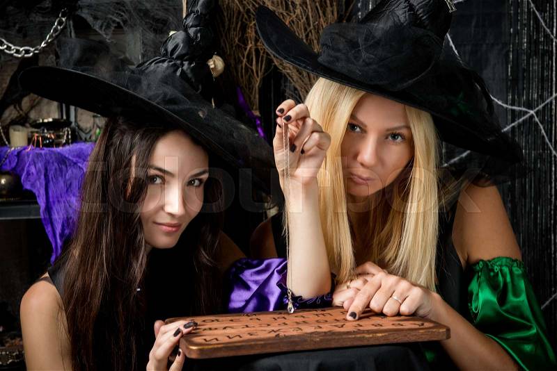 Two young witches guessing on a blackboard with letters, stock photo