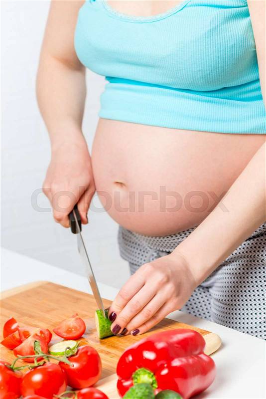 Female hands prepare vegetable salad in the kitchen, hands and stomach close-up, stock photo