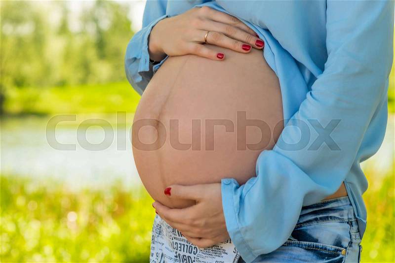 Beautiful big belly of a pregnant woman close-up, shooting in the park, stock photo