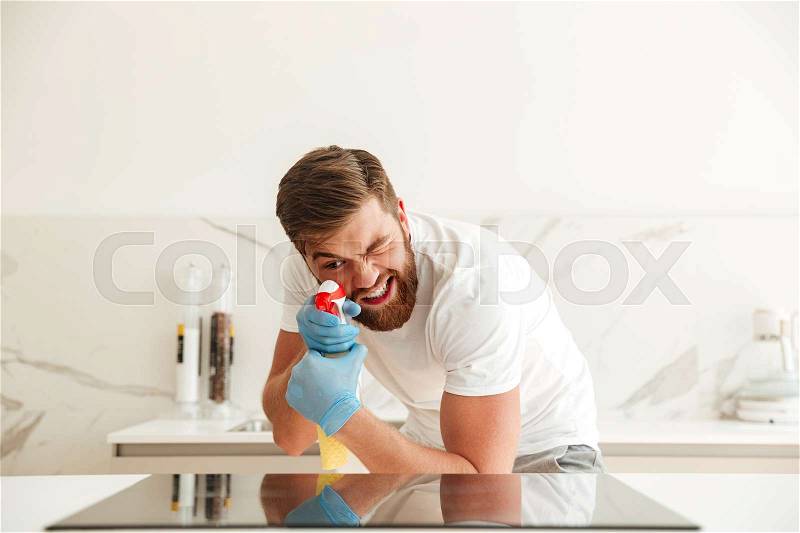 Funny bearded man with cleaners on kitchen at home, stock photo