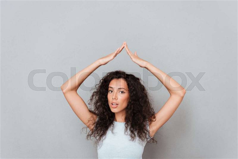 Confused woman hiding under hands like home isolated over grey, stock photo