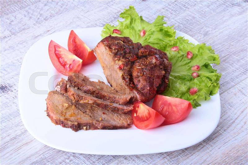 Steak of grilled meat with tomato, lettuce and beans pomegranate on white plate, stock photo