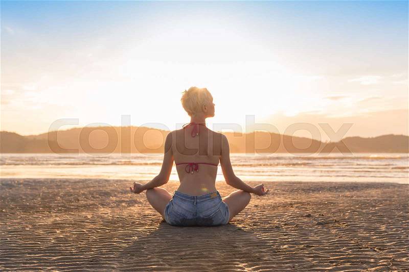 Young Girl Sitting Lotus Pose On Beach At Sunset, Beautiful Woman Practicing Yoga Summer Vacation Meditation Seaside Sea Ocean Holiday Travel, stock photo