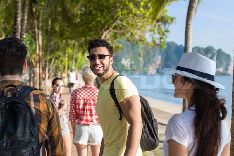People Group Walking In Palm Tree Park On Beach Talking, Casual Friends Tourists On Sea Summer Vacation, stock photo