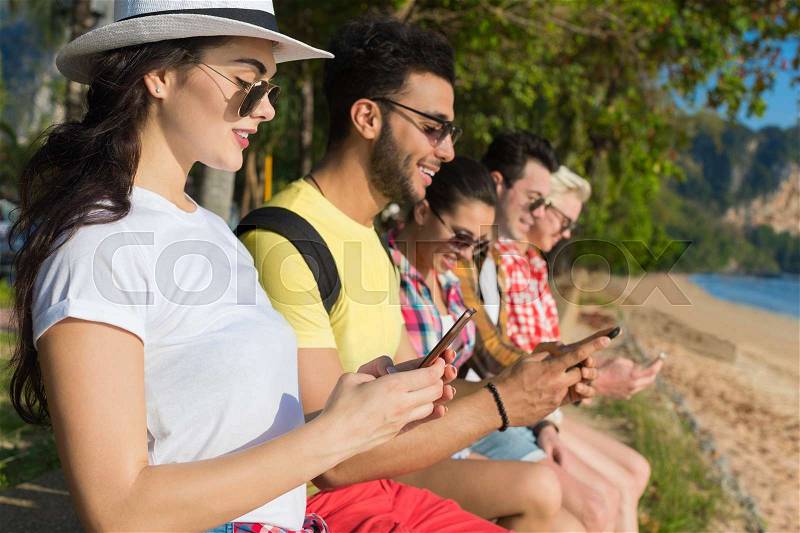 Young People Group Using Cell Smart Phones Tropical Park Palm Trees Friends Chatting Online Holiday Sea Summer Vacation Ocean Travel, stock photo
