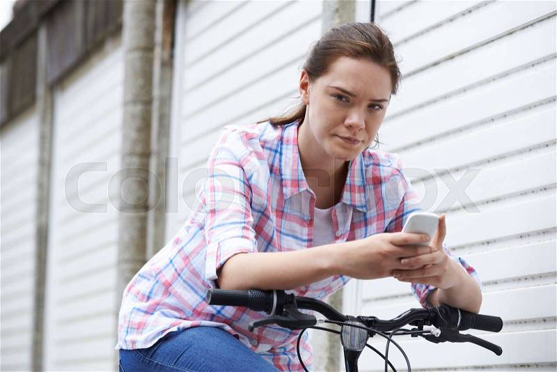Portrait Of Teenage Girl On Bike Texting Using Mobile Phone, stock photo