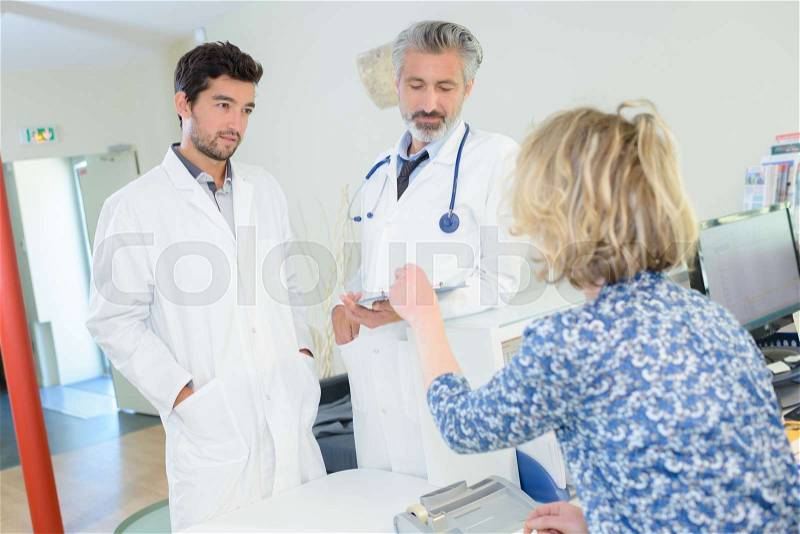 Two doctors and patient in medical cabinet, stock photo