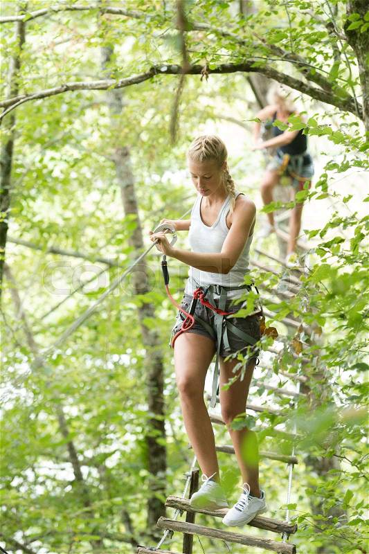 Cute girl climbing in the trees at adventure park, stock photo