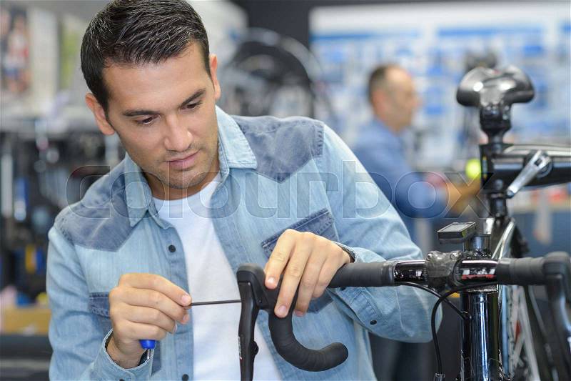 Happy man working on repairing bicycle using screwdriver tool, stock photo