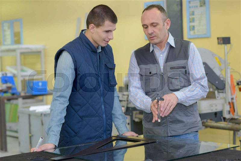 Portrait factory man teaching apprentice, stock photo