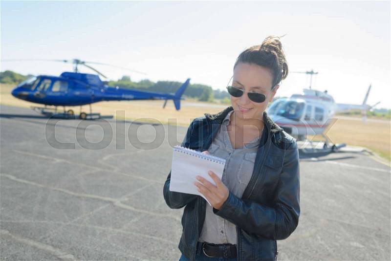 Pretty pilot woman on helicopter background, stock photo
