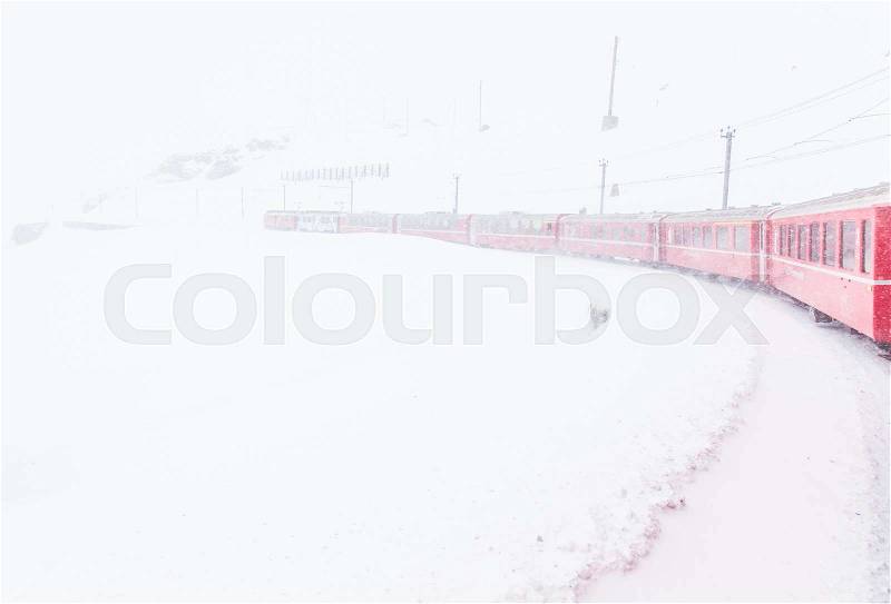The famous Bernina red train, Unesco monument, in the middle of a winter storm, stock photo