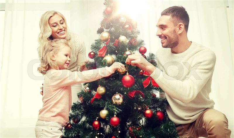 Family, x-mas, winter holidays and people concept - happy mother, father and little daughter decorating christmas tree at home, stock photo