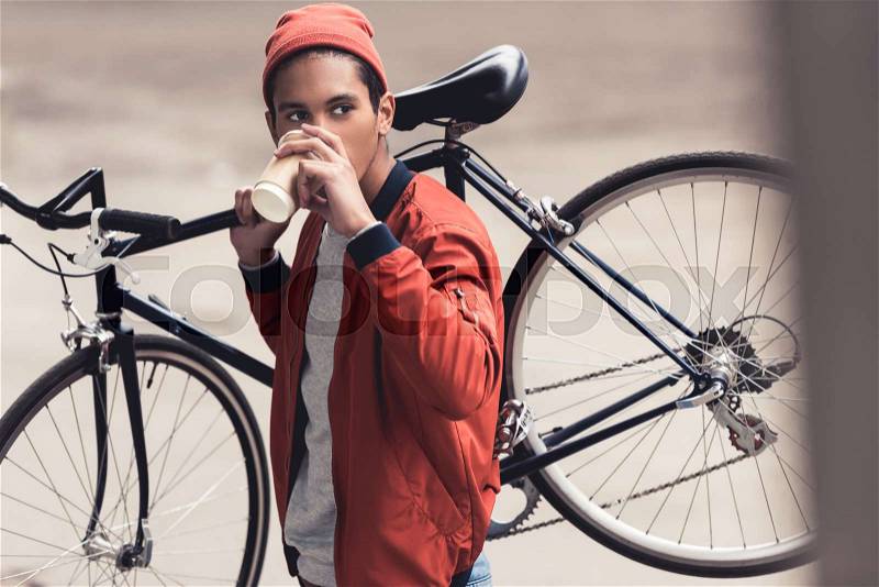 Man with vintage bicycle drinking coffee to go and looking away, stock photo