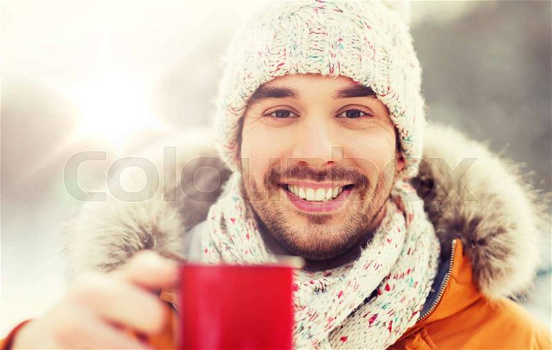 People, season, drinks and leisure concept - happy man with tea cup outdoors in winter, stock photo