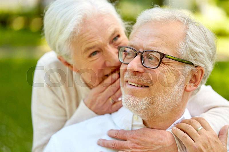 Old age, retirement and people concept - close up of happy senior couple whispering outdoors, stock photo