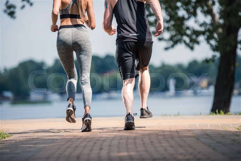 Partial view of sportive couple jogging together in park, stock photo