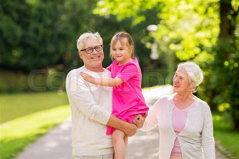 Family, generation and people concept - happy smiling grandmother, grandfather and little granddaughter at park, stock photo